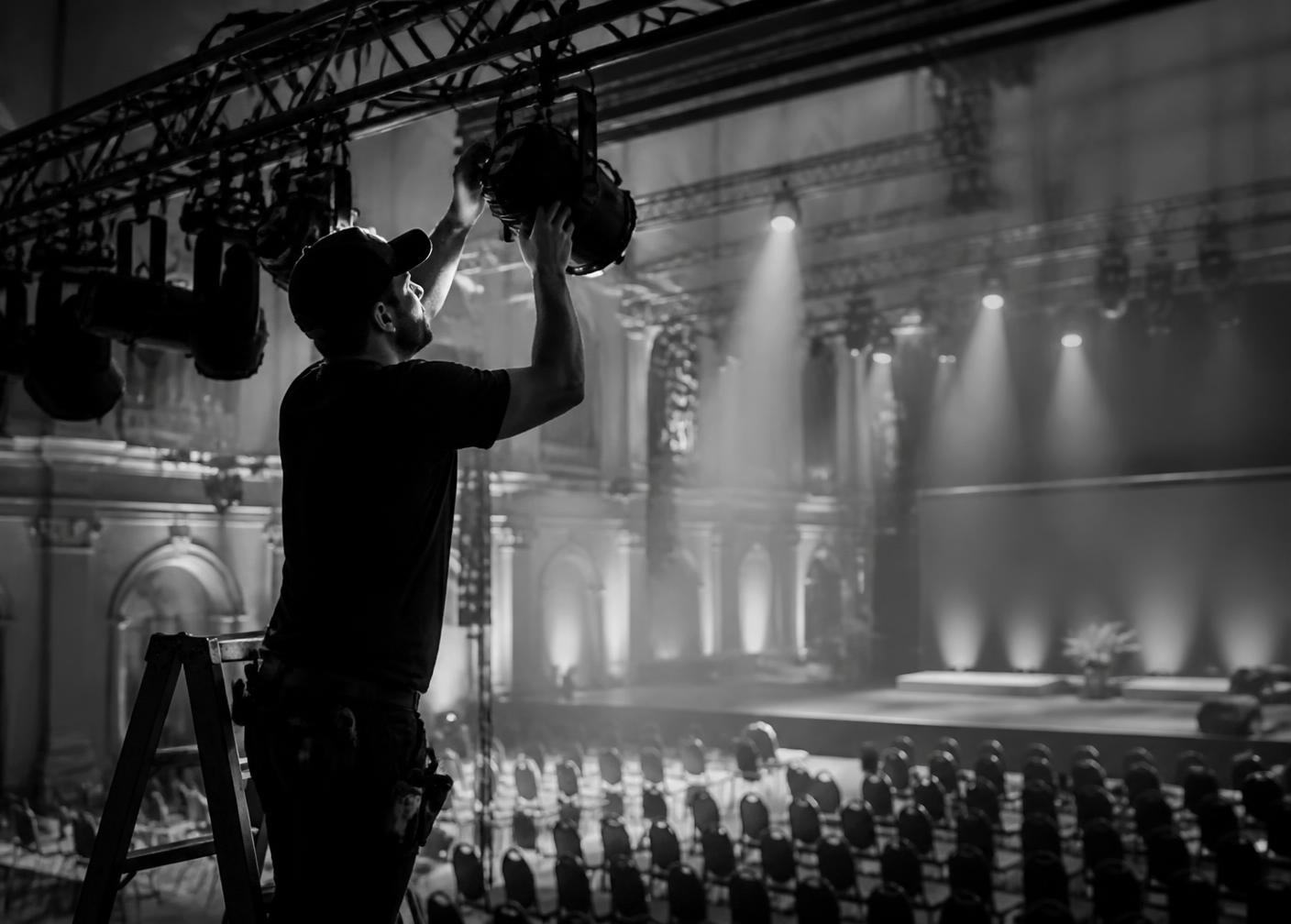 A production technician preparing stage lighting in an event venue